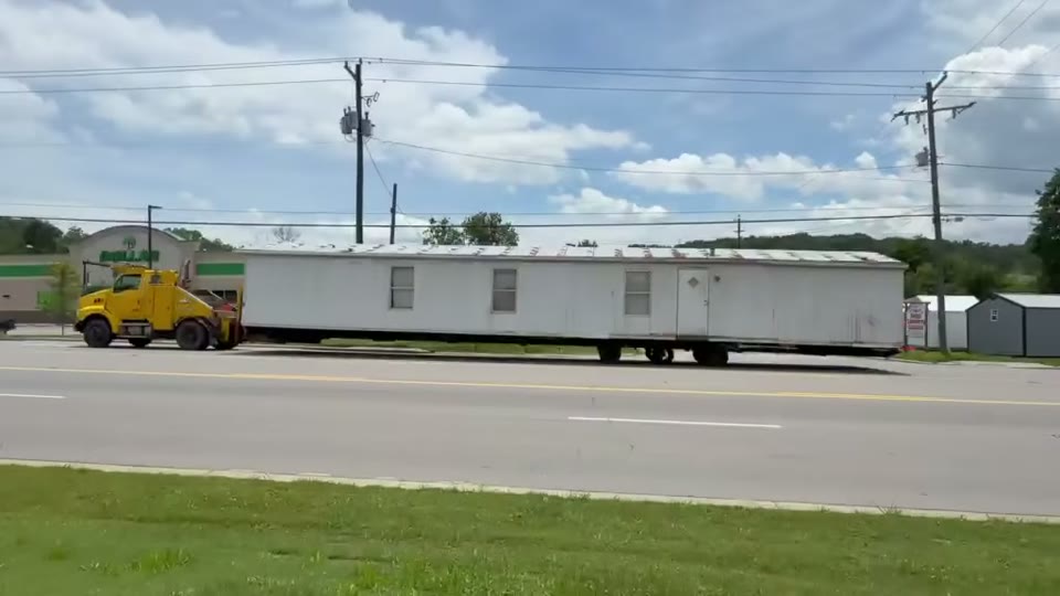 Our yellow truck pulling a white single-wide down the highway. Built by Asheville Modular and Mobile Home Services.